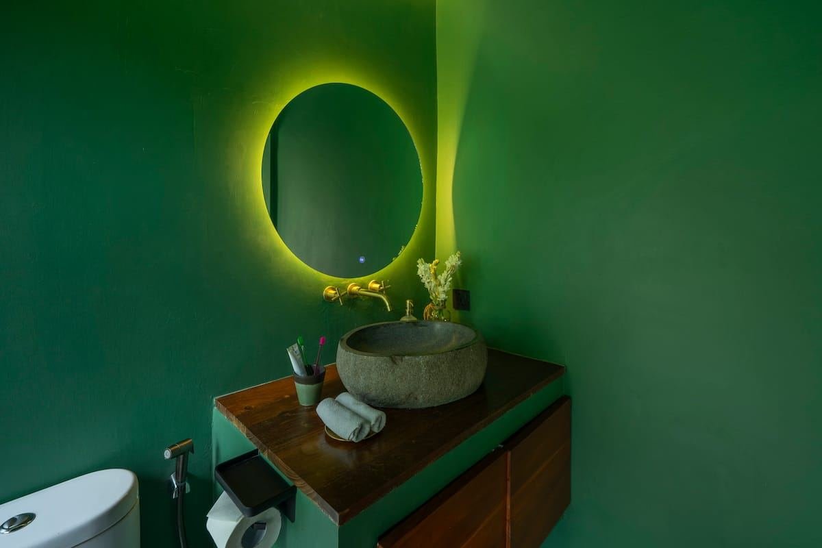 Bathroom with a round lit mirror and stone basin