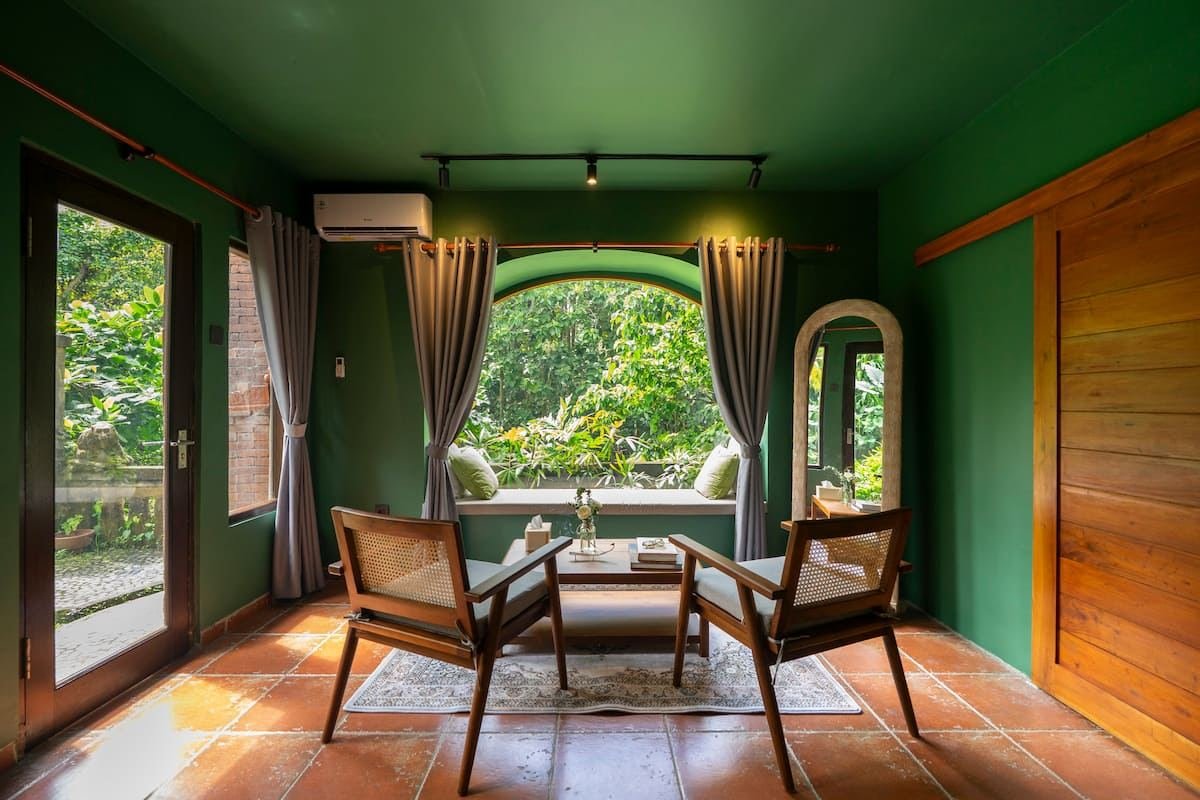 Two chairs by the arched bay window, looking out over the forest