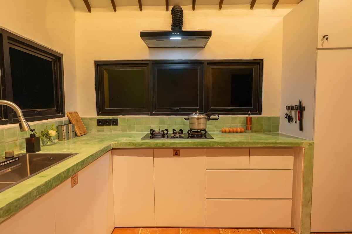 The renovated kitchen with gas hob and green tiled counters